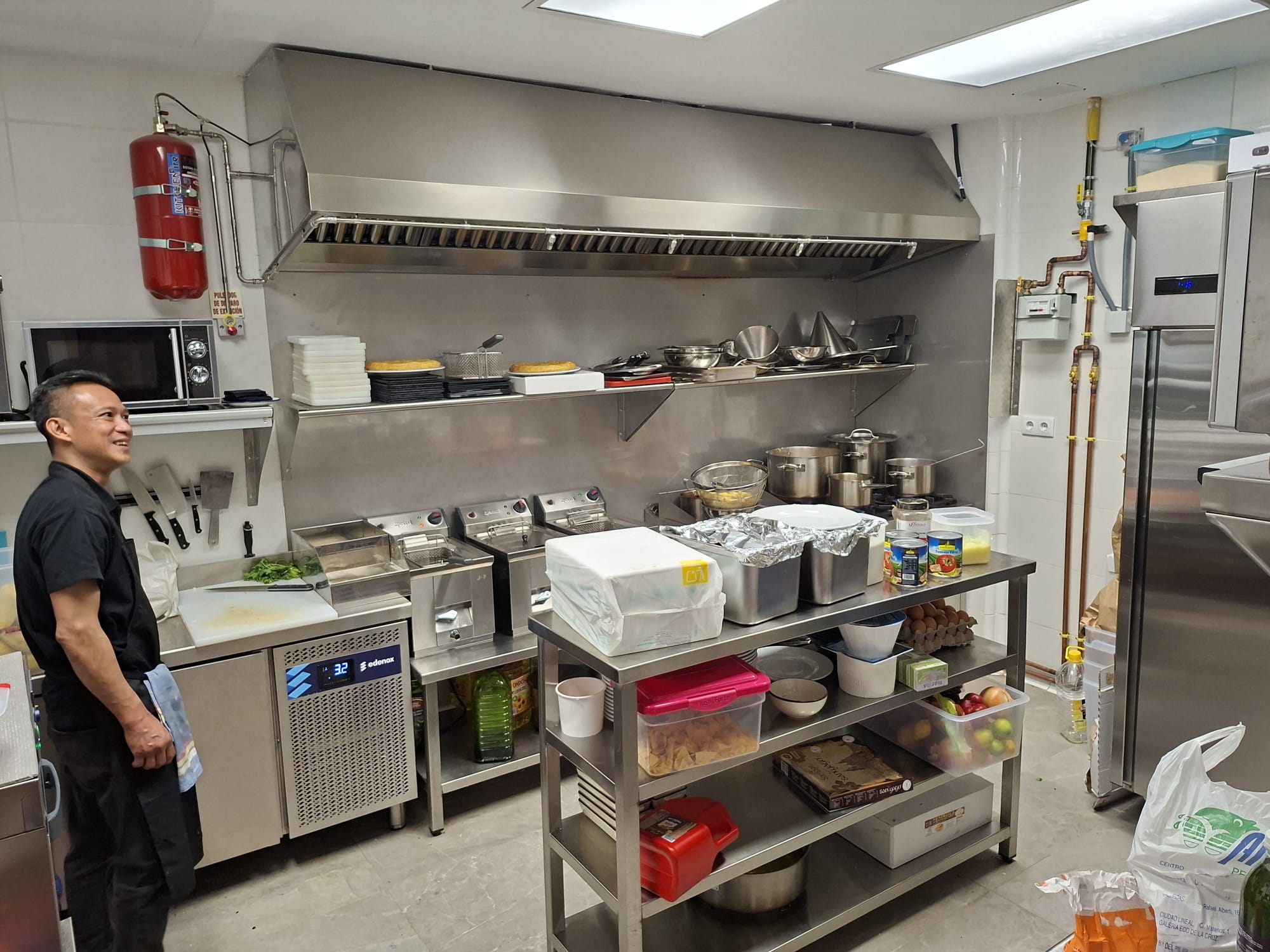 Cocina industrial con superficies de acero y pasaplatos iluminado.
